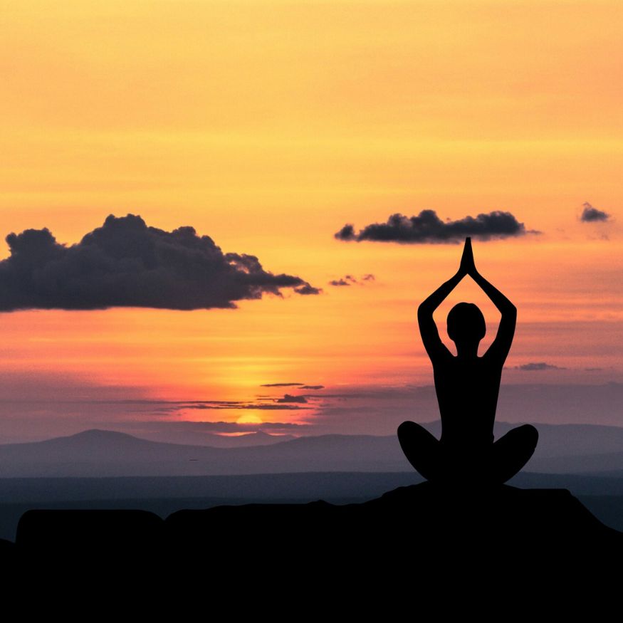 Femme de dos méditant face à un coucher de soleil, illustrant l'harmonie du Yin et du Yang pour le bien-être et la santé