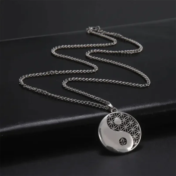 une image montrant Un pendentif Mystique Yin Yang circulaire en argent suspendu à une chaîne, affichant le symbole du Yin Yang avec une moitié embellie de motifs géométriques complexes pour une touche mystique posé sur un fond noir